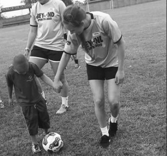 Stephens takes part in the service proj- ect as she teaches a child to play soccer (photo courtesy of Shelby Stephens).