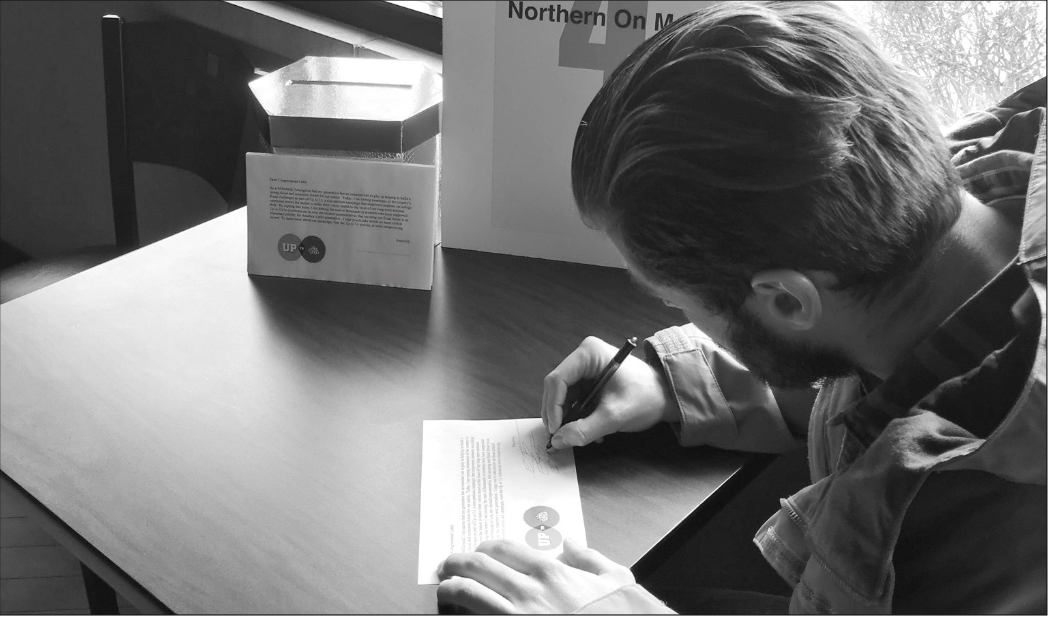 Up to Us team member, Evan Bader, signs the pledge for the competition. (photo/ Patrick Riley)
